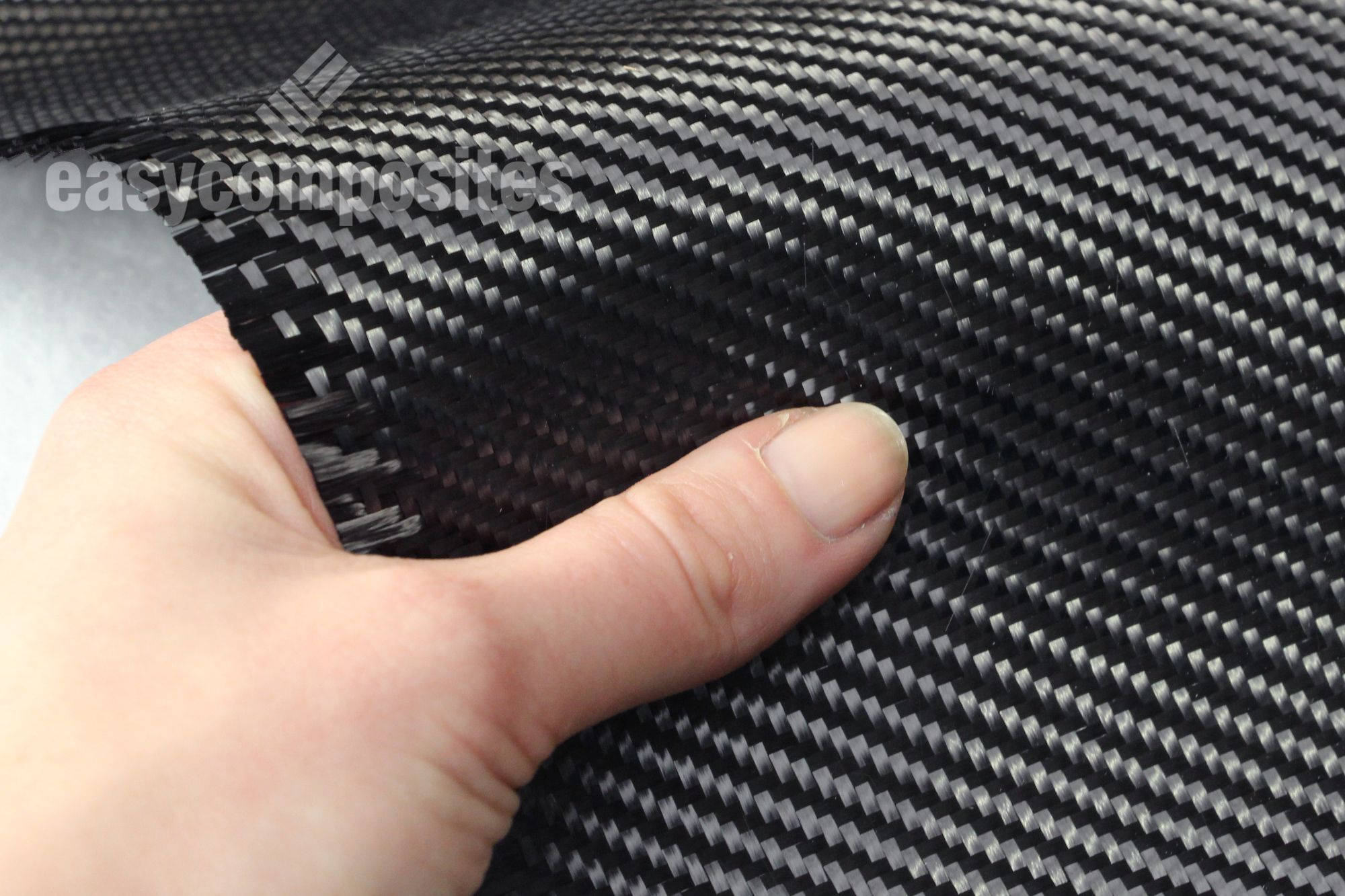 https://media.easycomposites.co.uk/products/extralarge/CF-22-240-240g-2x2-twill-3k-carbon-fibre-in-hand-closup.jpg